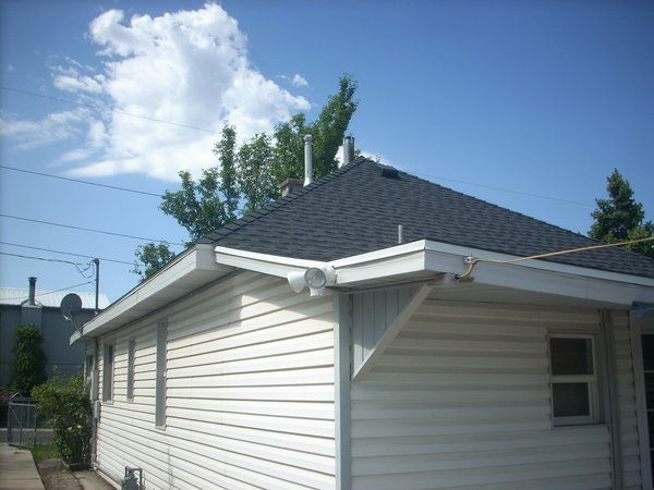 White house exterior with gray roof and siding under a blue sky with clouds