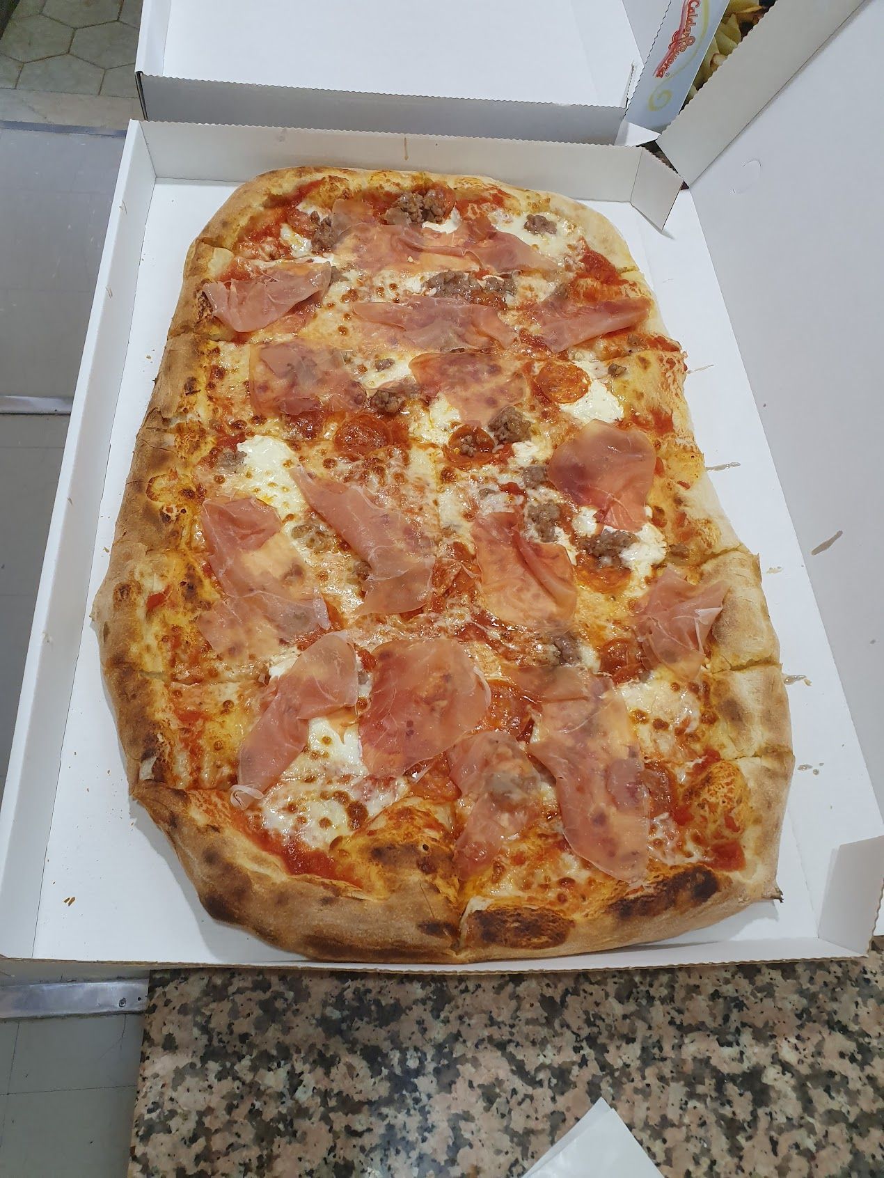In una scatola c'è una pizza con prosciutto e formaggio