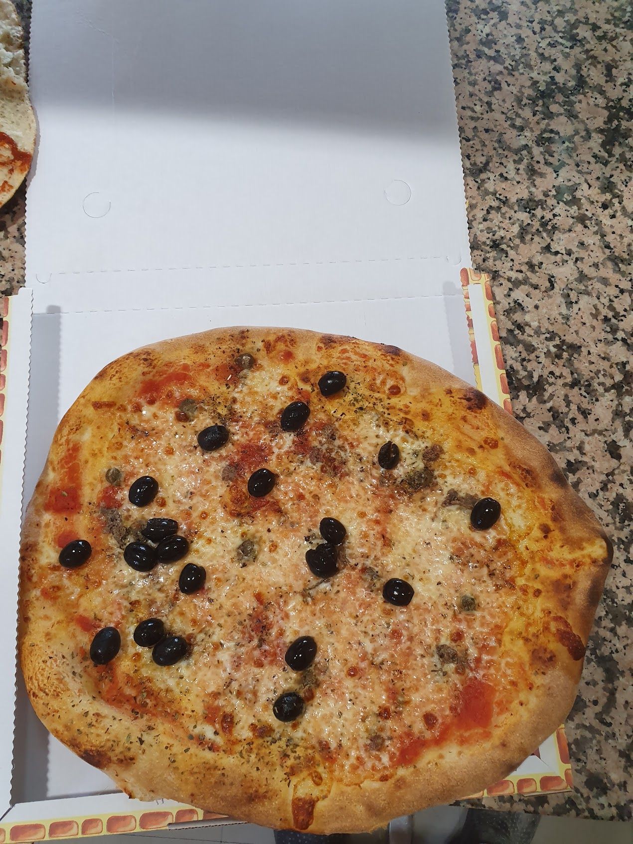In una scatola c'è una pizza con le olive sopra