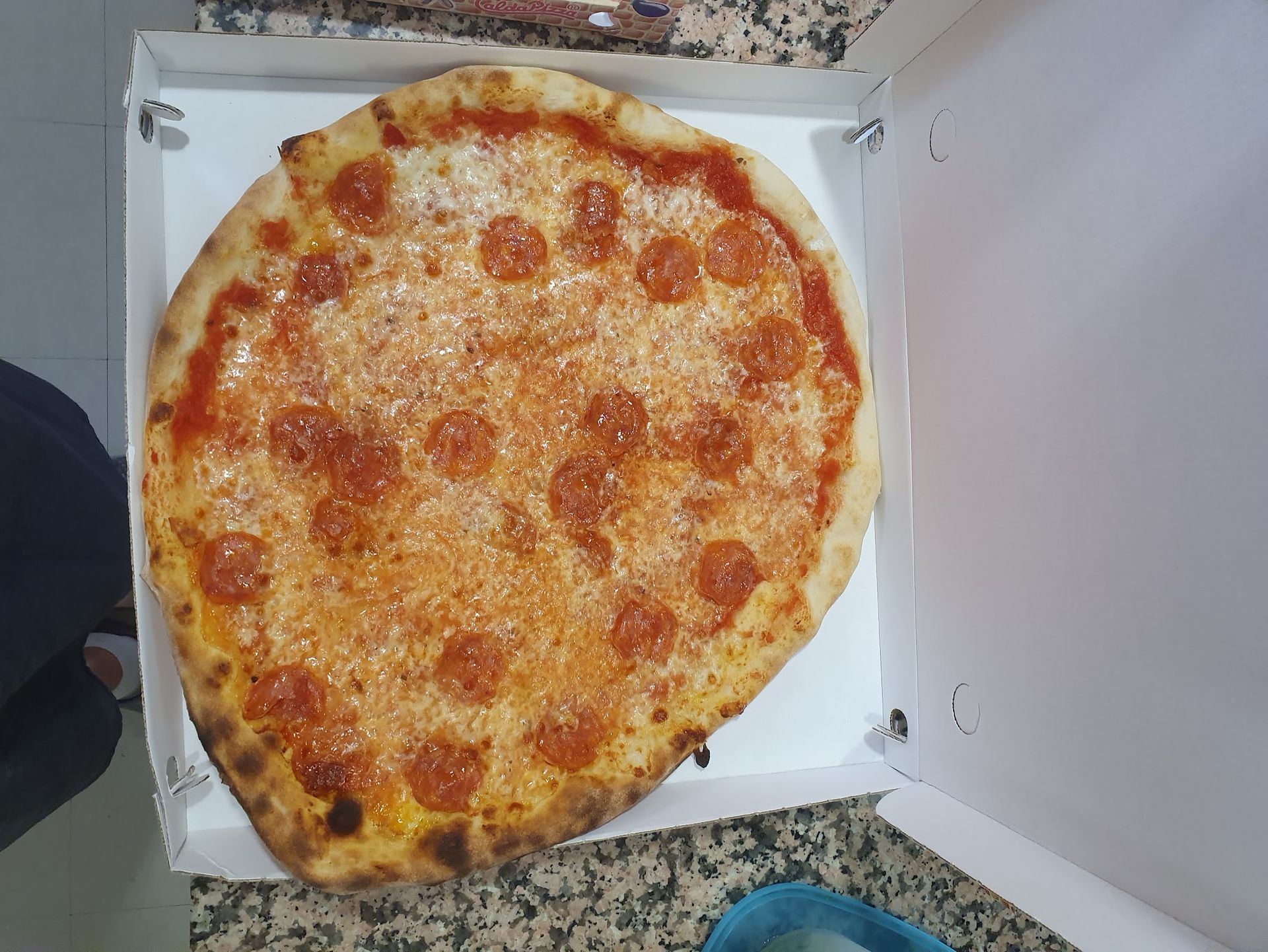 Una pizza ai peperoni è in una scatola bianca sul bancone.