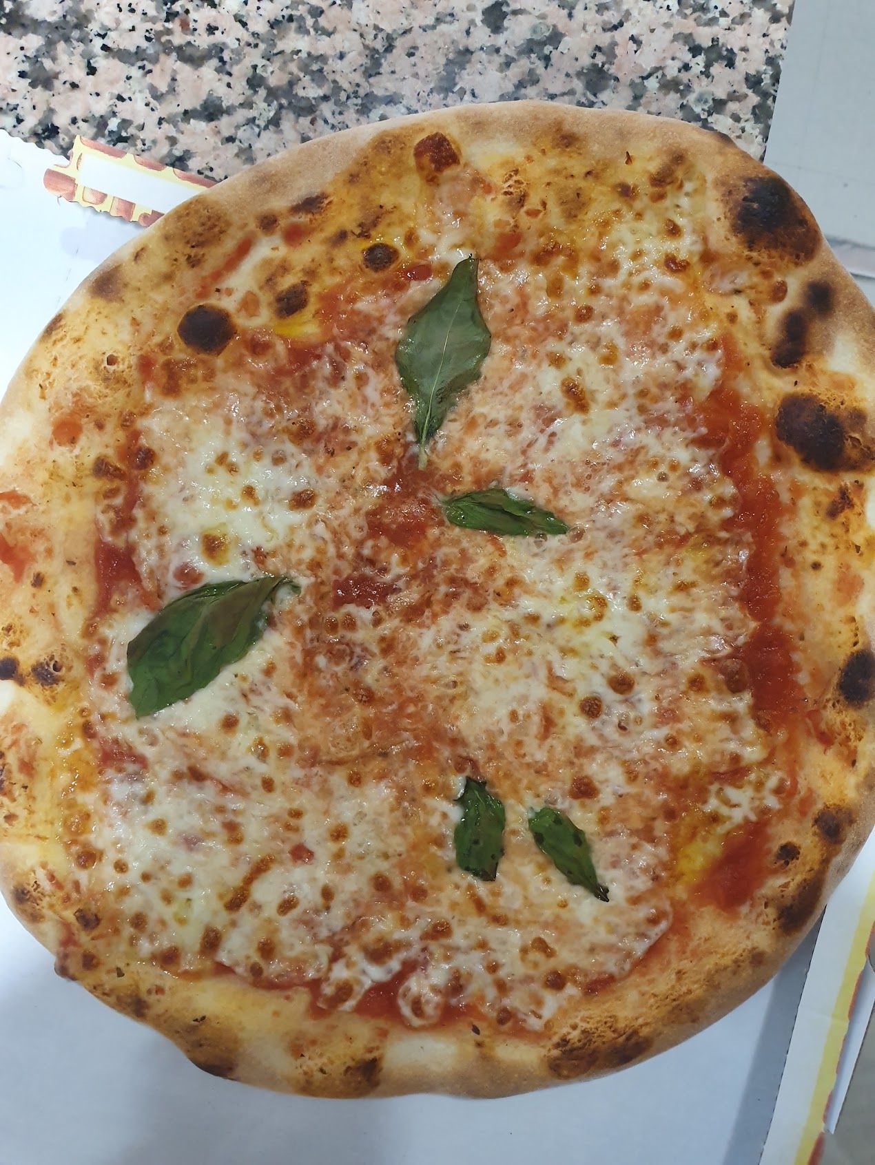 Su un tavolo è seduta una pizza con salsa di pomodoro e formaggio.