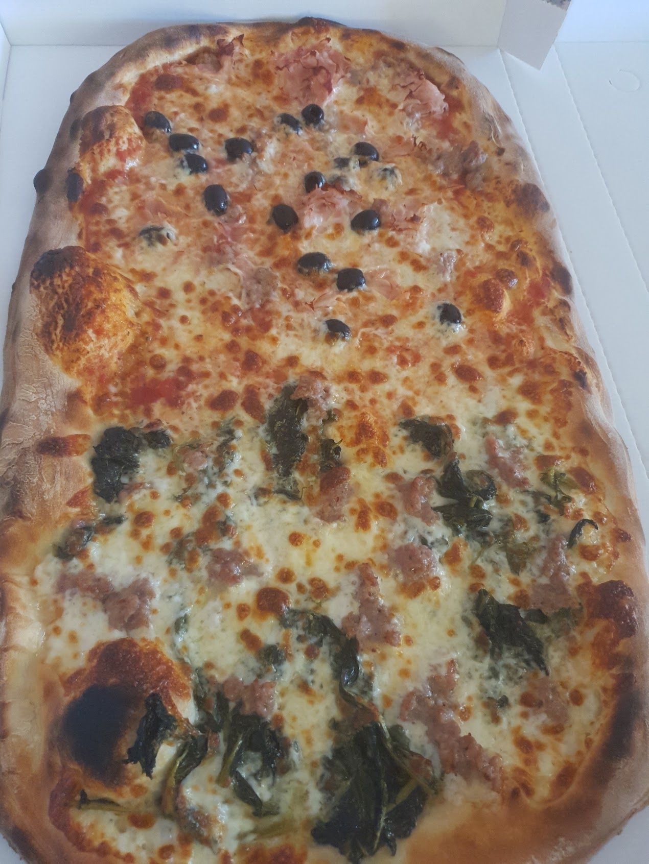 Una grande pizza è seduta in una scatola su un tavolo.