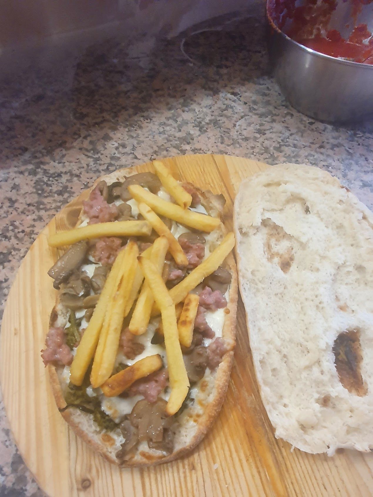 Una pizza con patatine fritte è su un tagliere di legno.