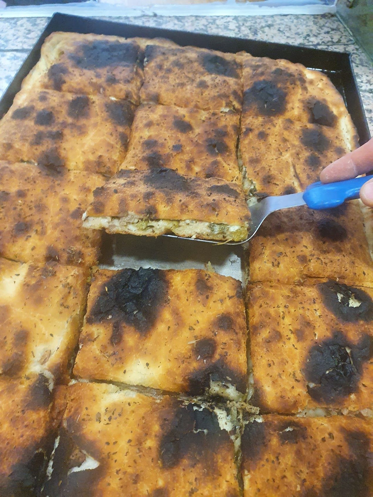 Una persona taglia un pezzo di pizza con una spatola.