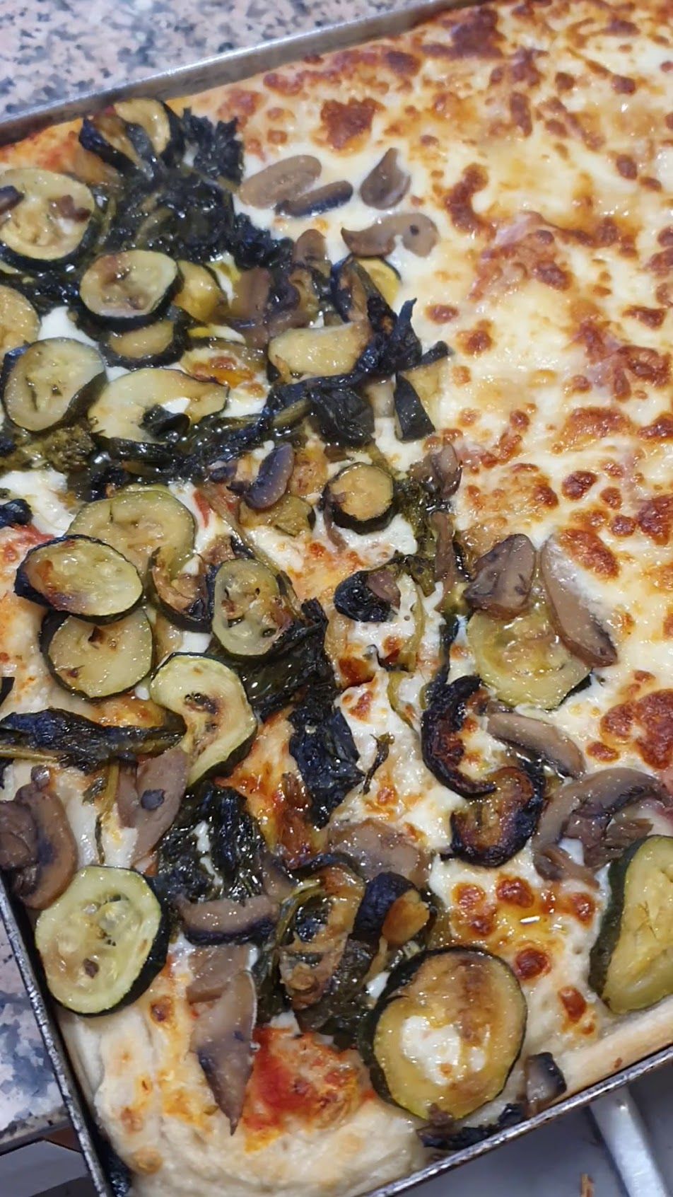 Su un tavolo è seduta una pizza con molte verdure sopra.