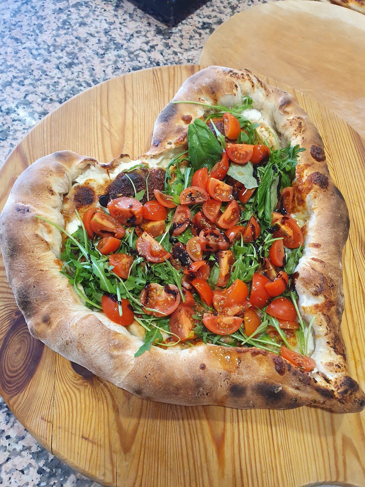 Una pizza a forma di cuore su un tagliere di legno