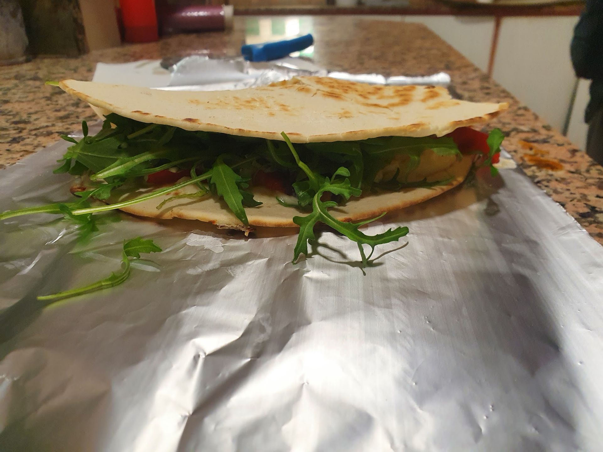 Un panino è avvolto nella carta stagnola su un bancone.