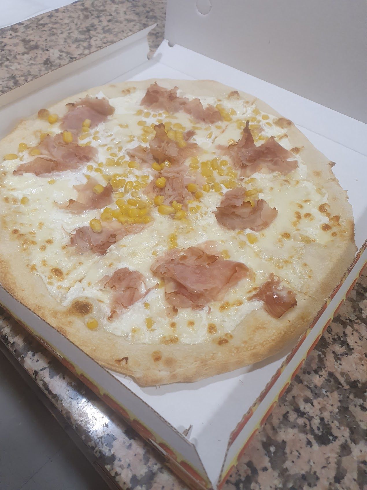 Una pizza è seduta in una scatola su un bancone.