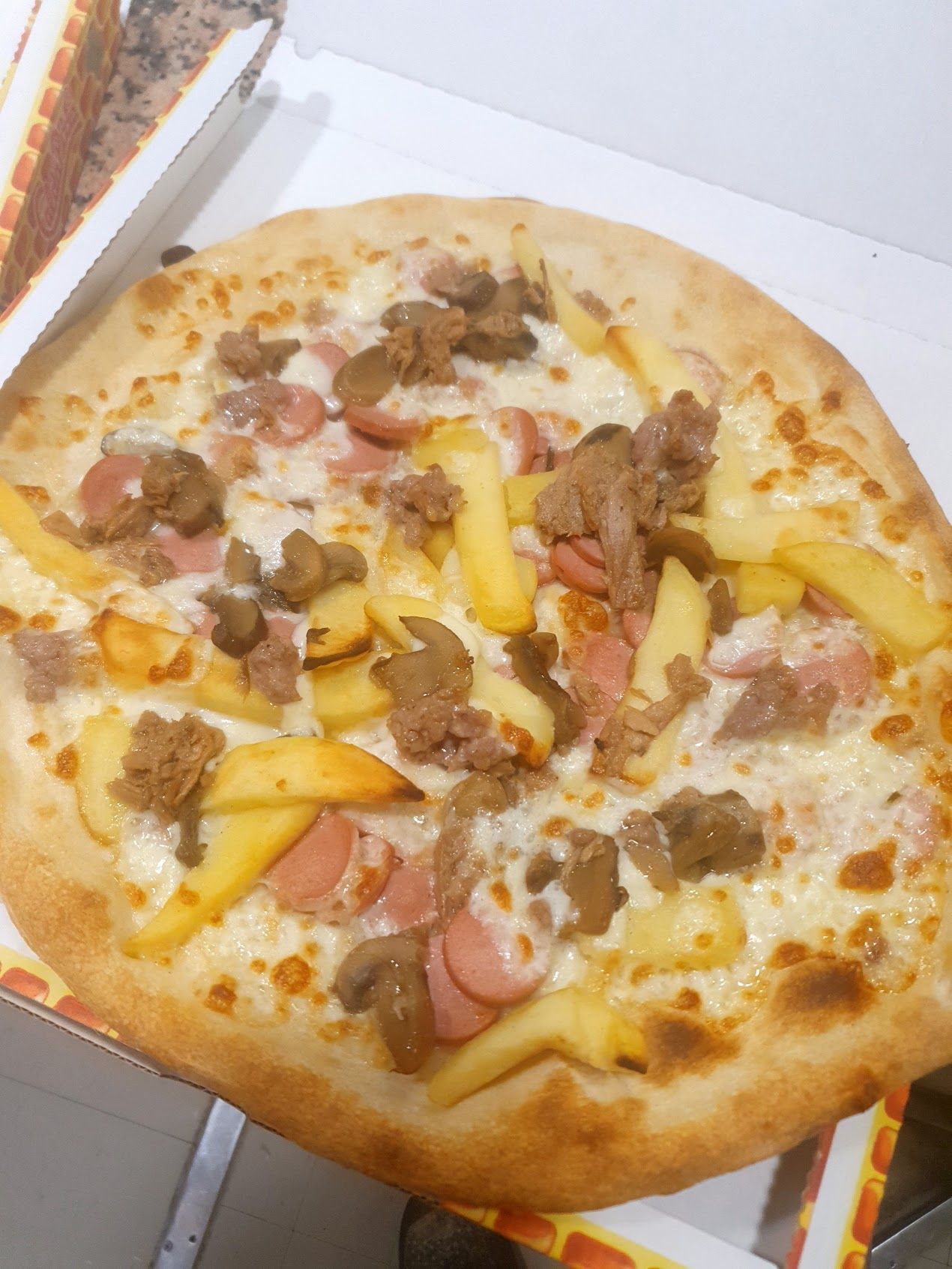 Una pizza con patatine fritte e salsiccia sopra