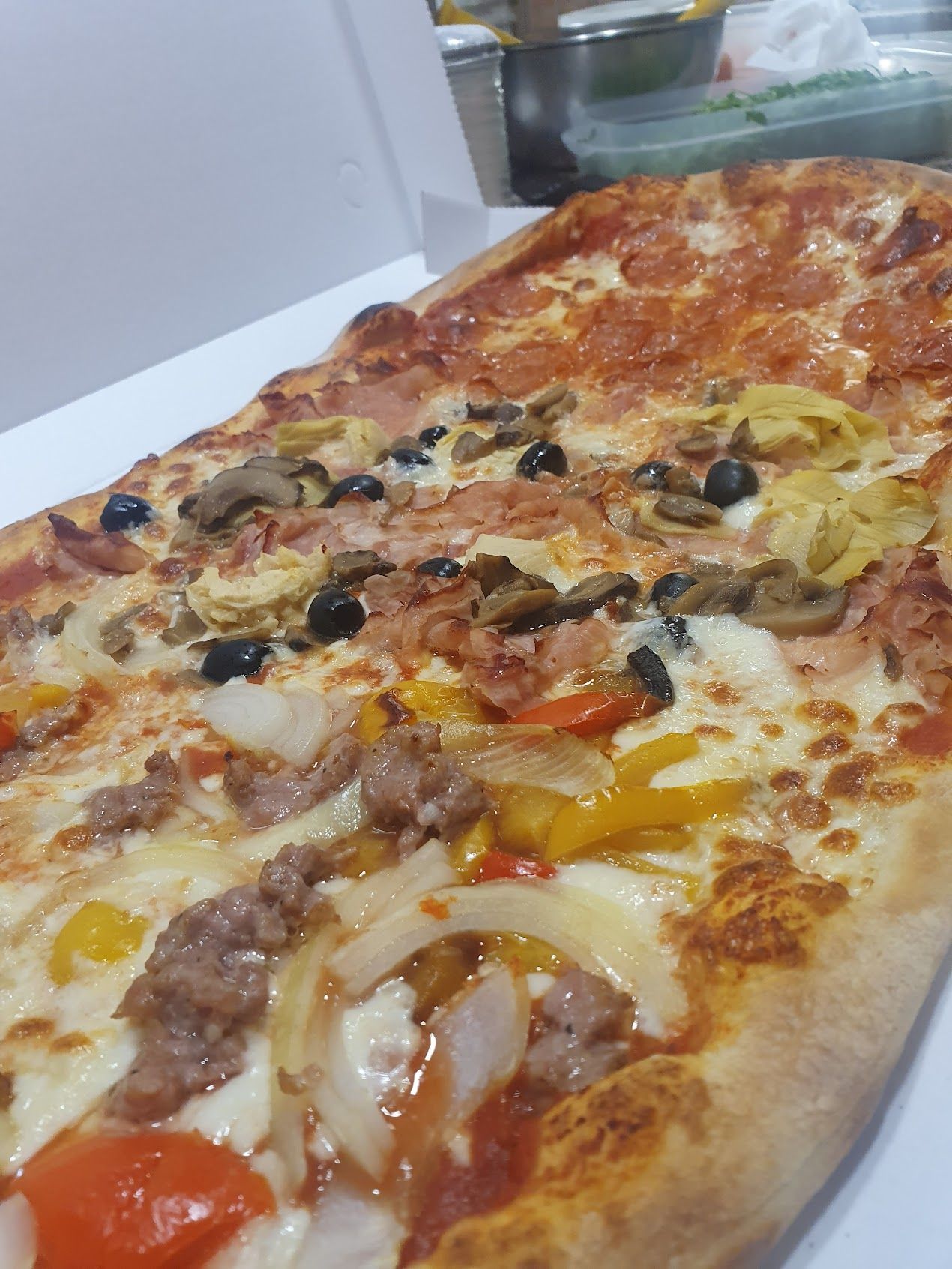 Una pizza con molti condimenti è su un piatto bianco.