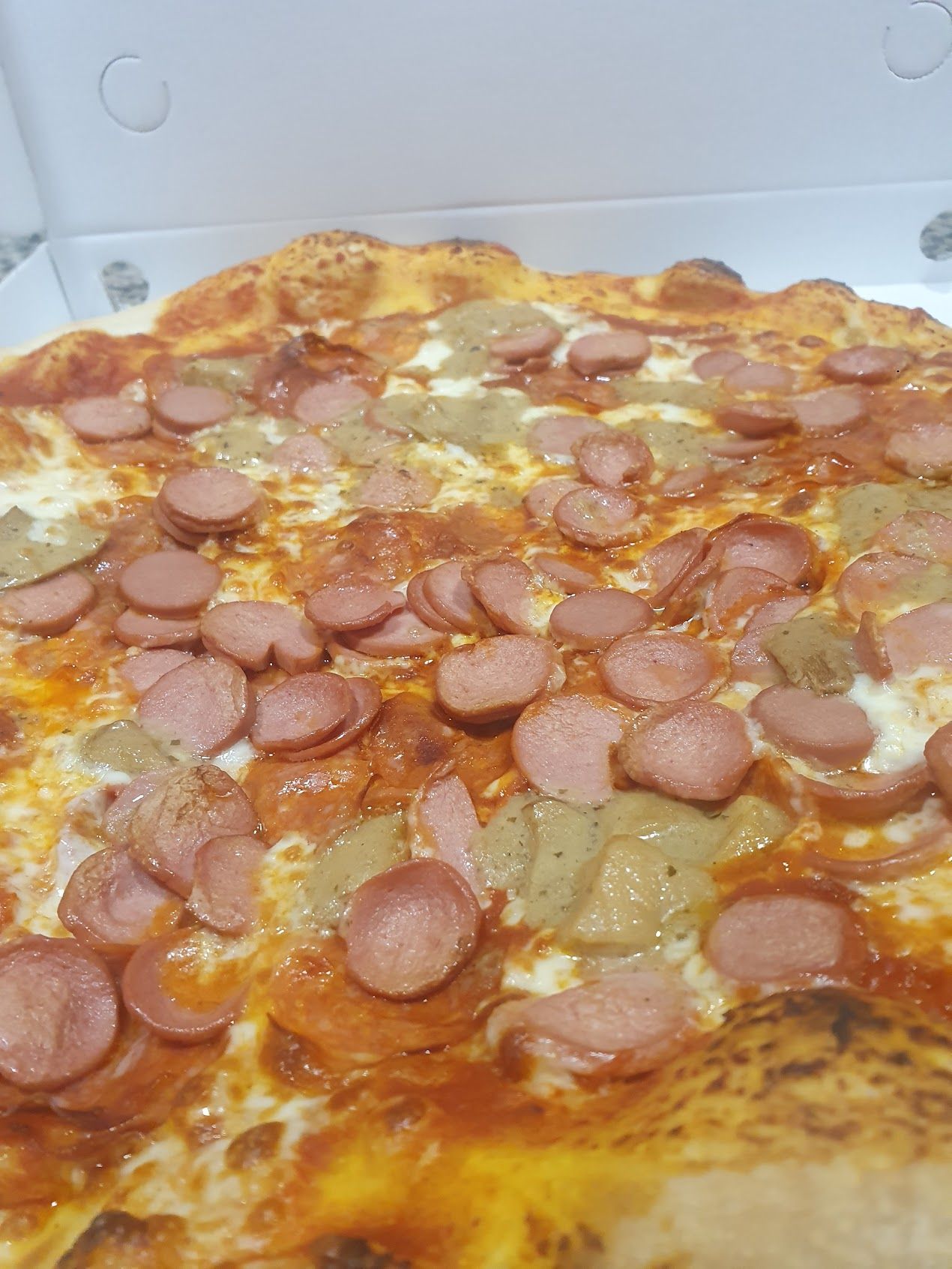 Un primo piano di una pizza con salsiccia e formaggio in una scatola.