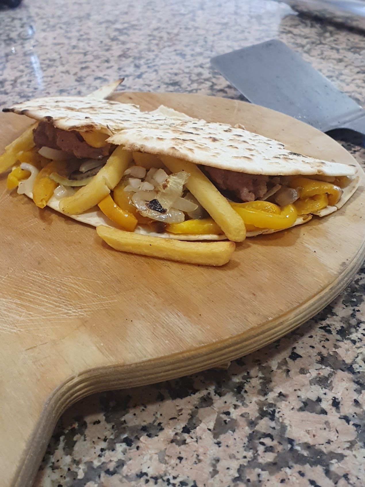Una tortilla con patatine fritte e formaggio su un tagliere di legno