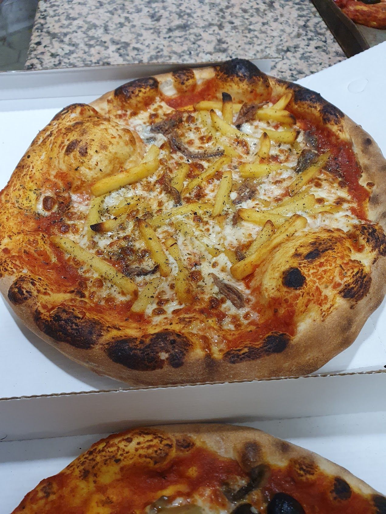 In una scatola c'è una pizza con patatine fritte