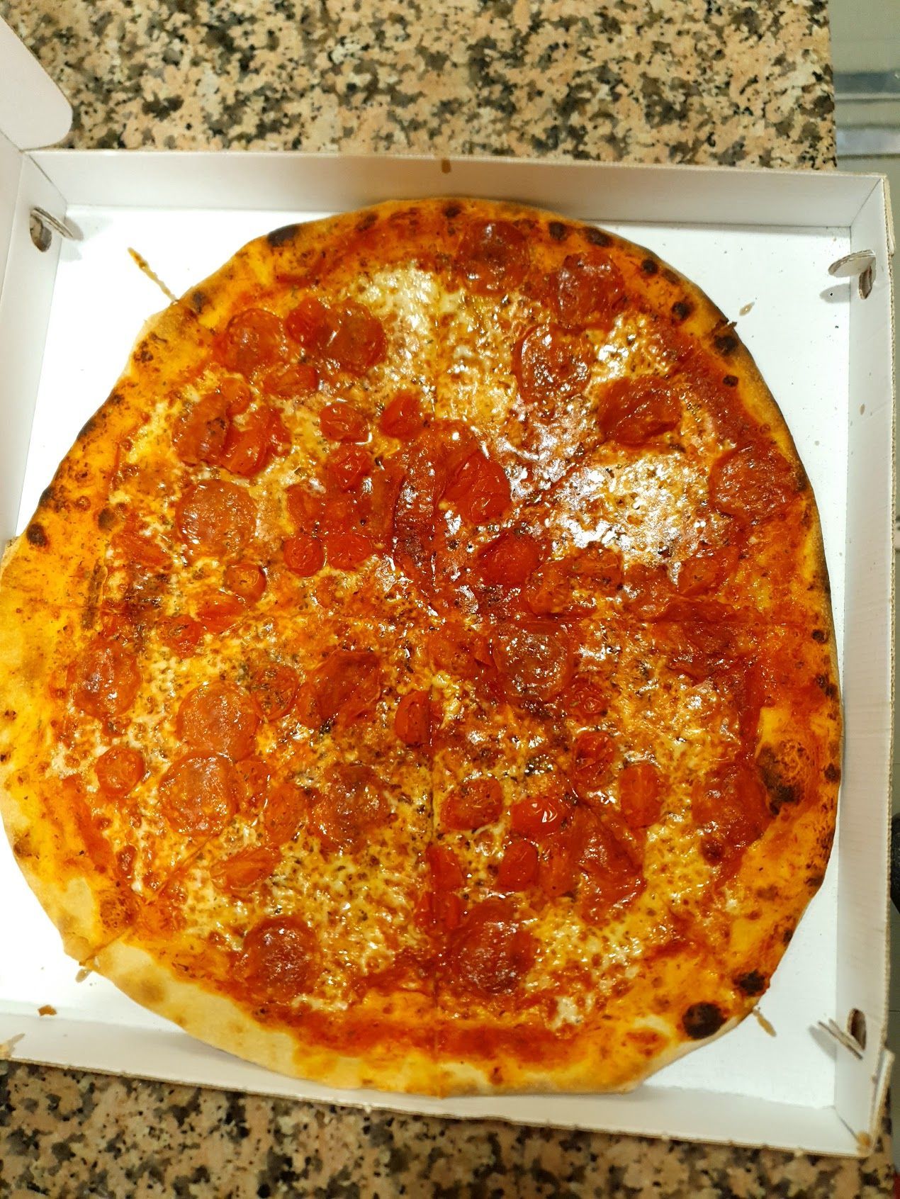 Una pizza ai peperoni è in una scatola sul bancone