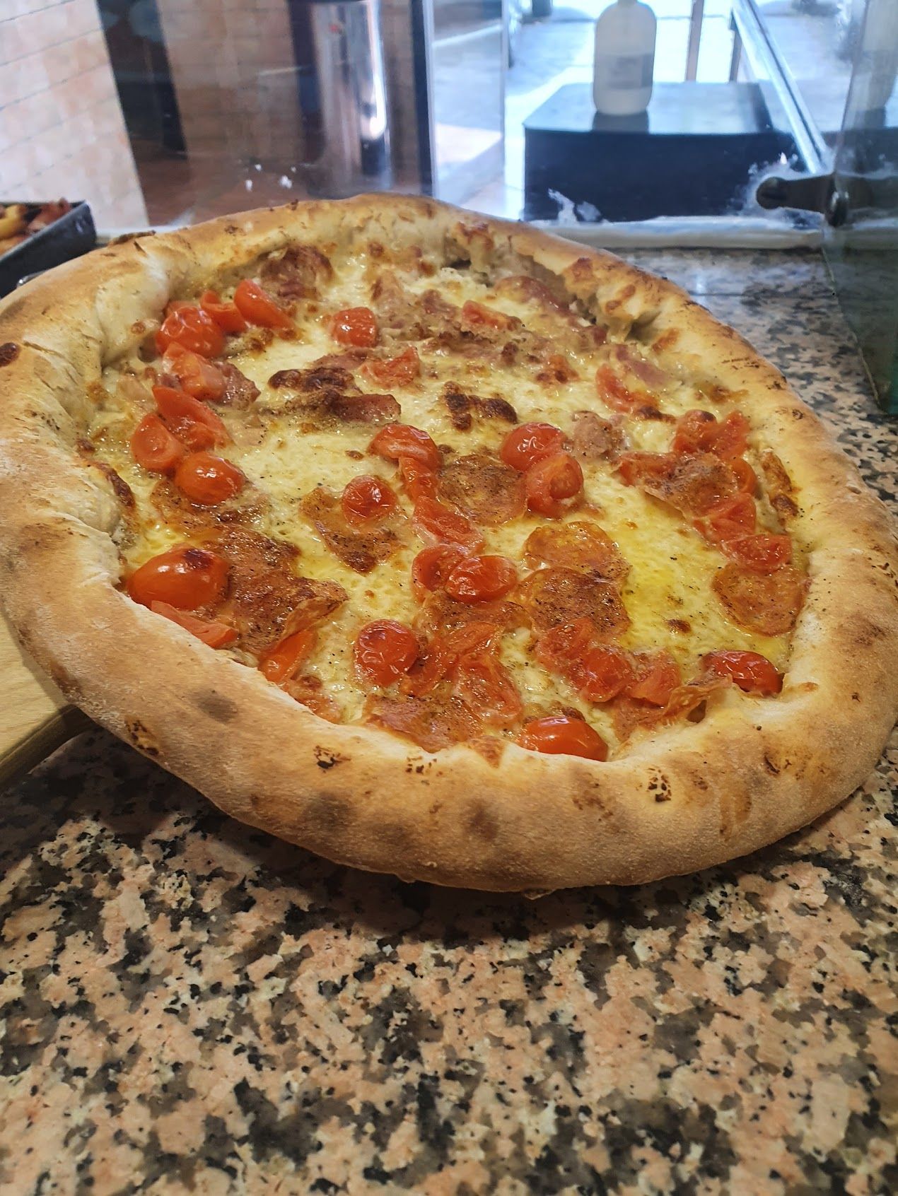 Su un bancone c'è una pizza con pomodoro e formaggio.