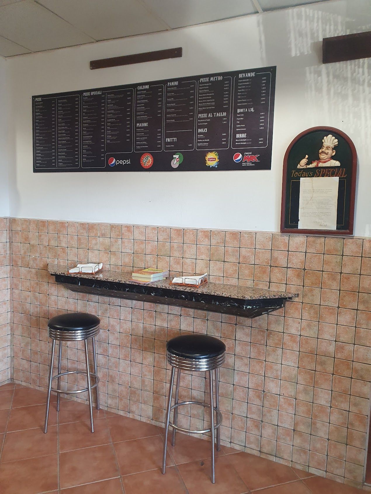 Un ristorante con sgabelli e un menù appeso al muro