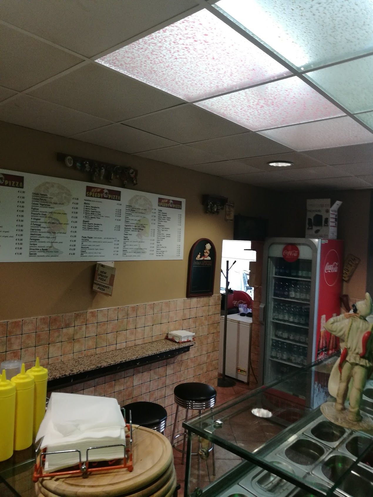 Un ristorante con un menù appeso al muro e un frigo con la coca cola