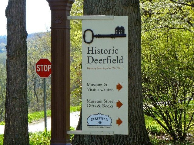 A stop sign next to a sign for historic deerfield