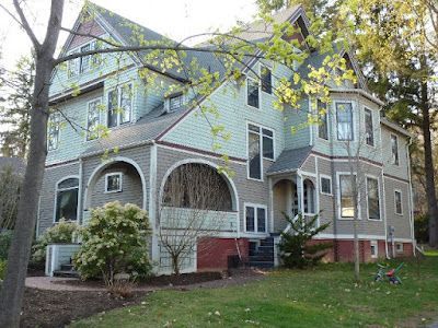 A large house with a lot of windows is surrounded by trees.