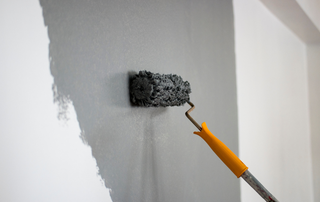 A person is painting a wall with a paint roller.