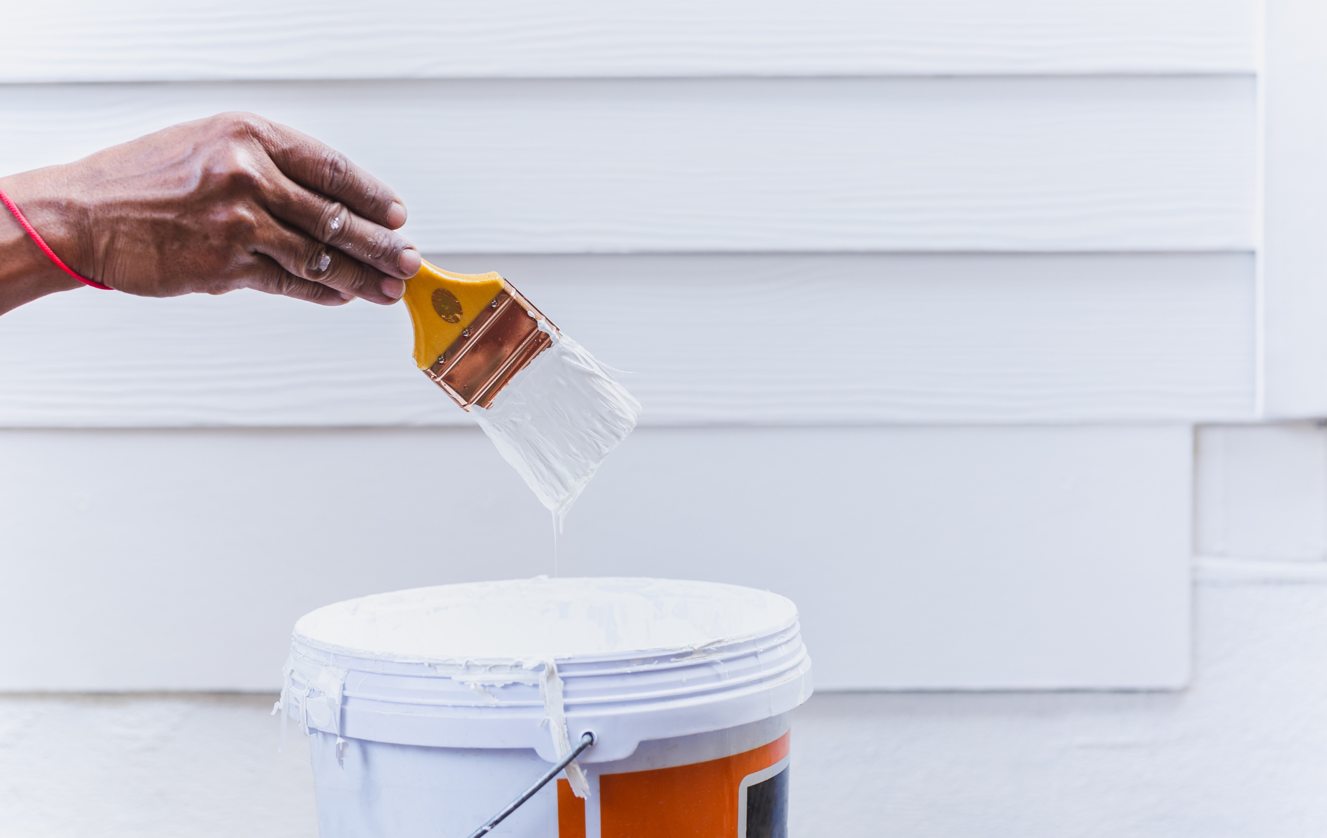 A person is pouring paint from a brush into a bucket.