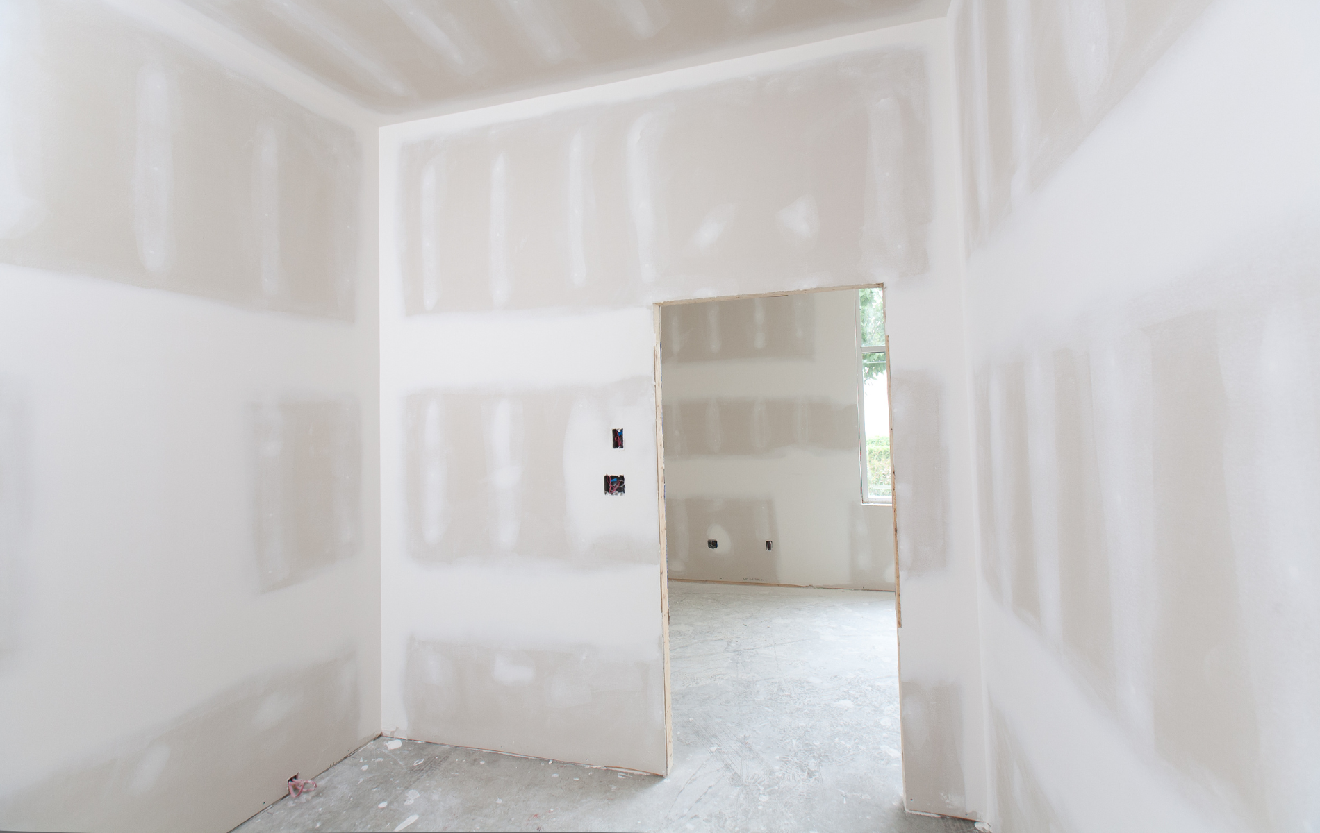 An empty room with drywall walls and a door.