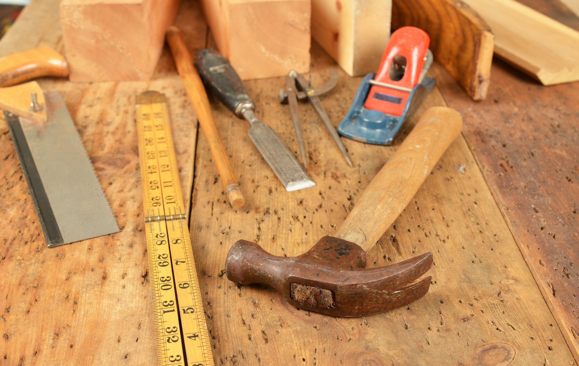 A hammer is sitting on a wooden table with other tools