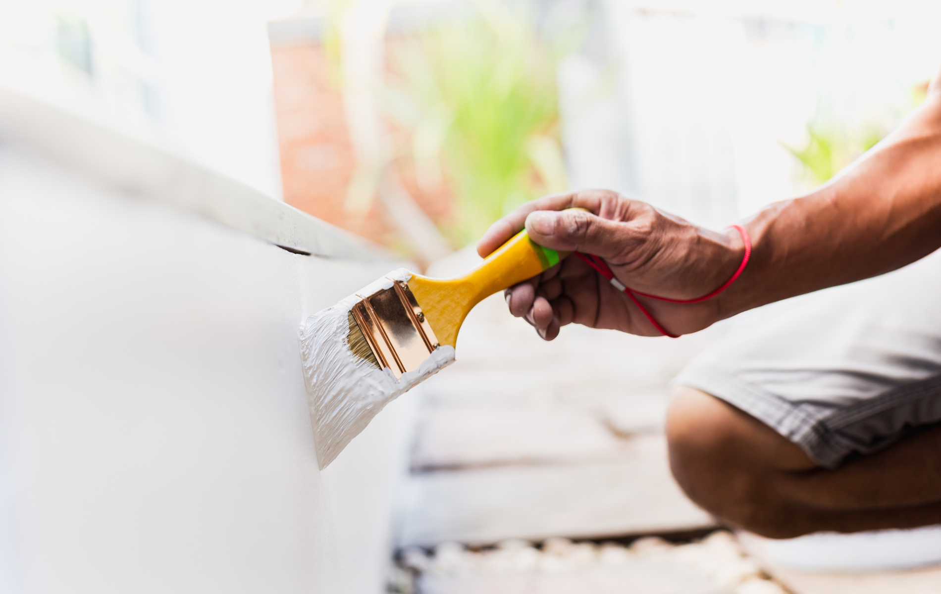 A man is painting a wall with a paint brush.