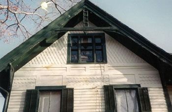 A white house with black shutters and a green roof
