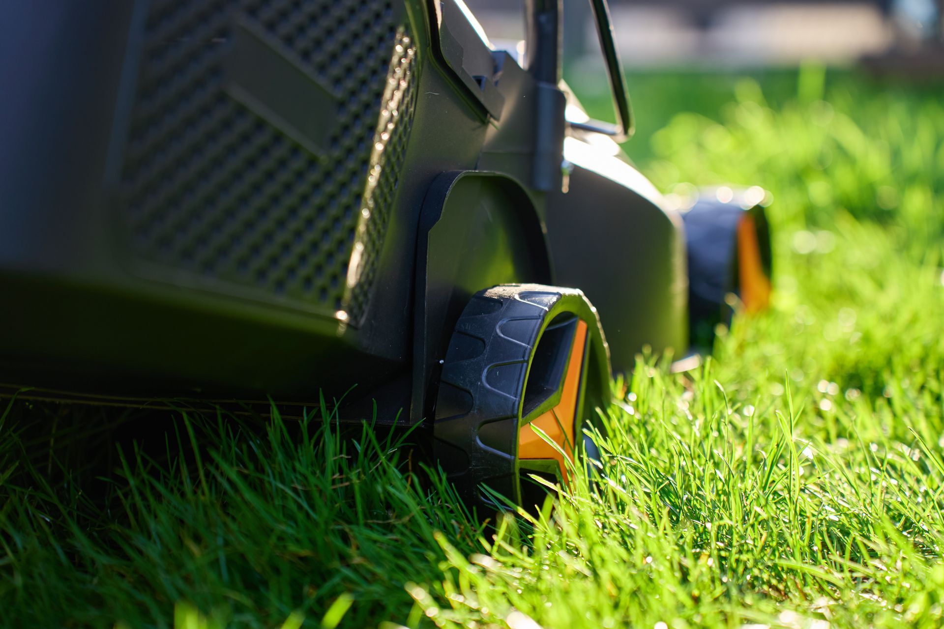 Close-up of a lawn mower wheel rolling through bright green grass