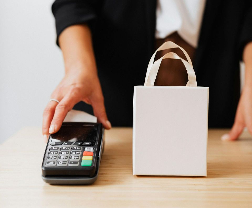 A woman is using a credit card machine to pay for a shopping bag.