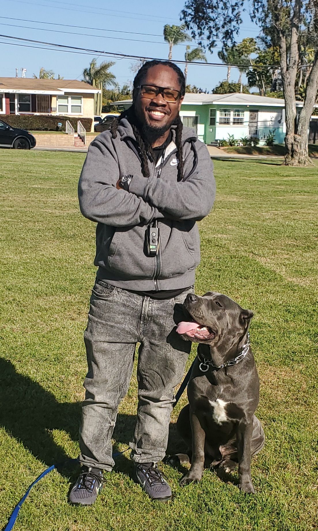 A man is standing next to a dog in a grassy field.