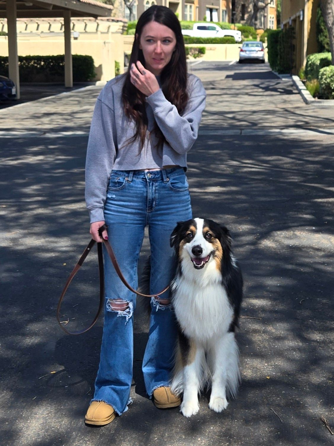 A woman is standing next to a dog on a leash.