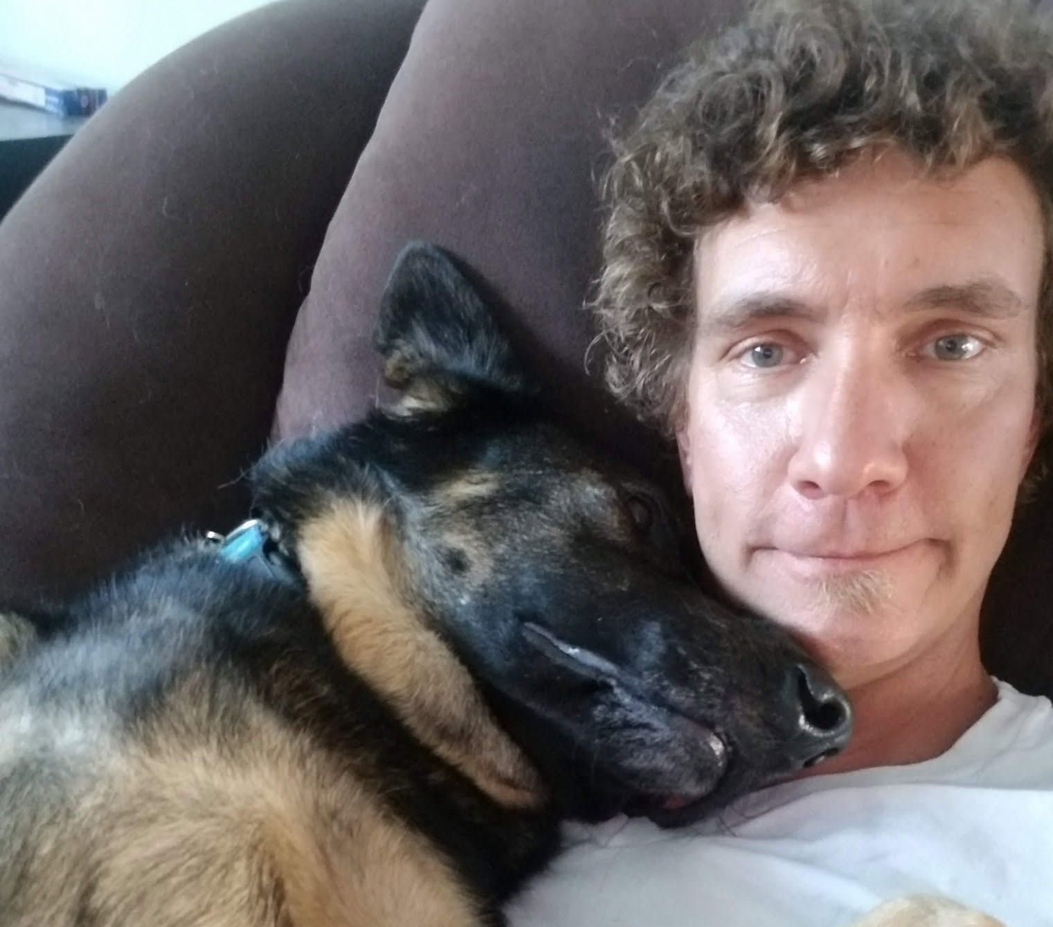 A man is laying on a couch with his dog