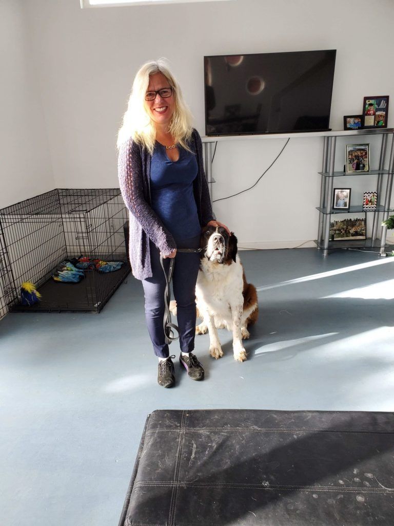 A woman is standing next to a dog on a leash