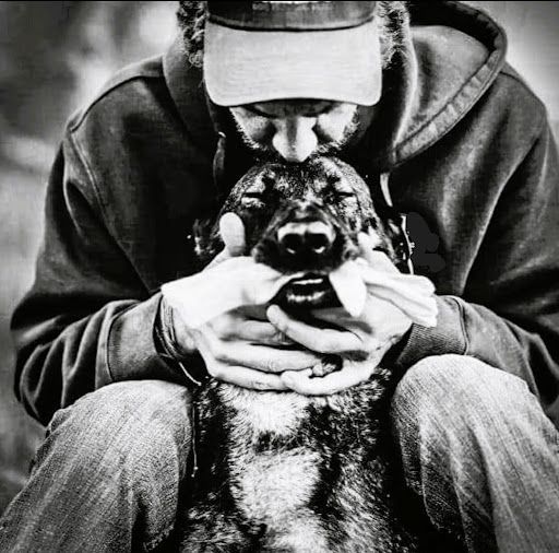 A man is kissing a dog on the nose in a black and white photo.