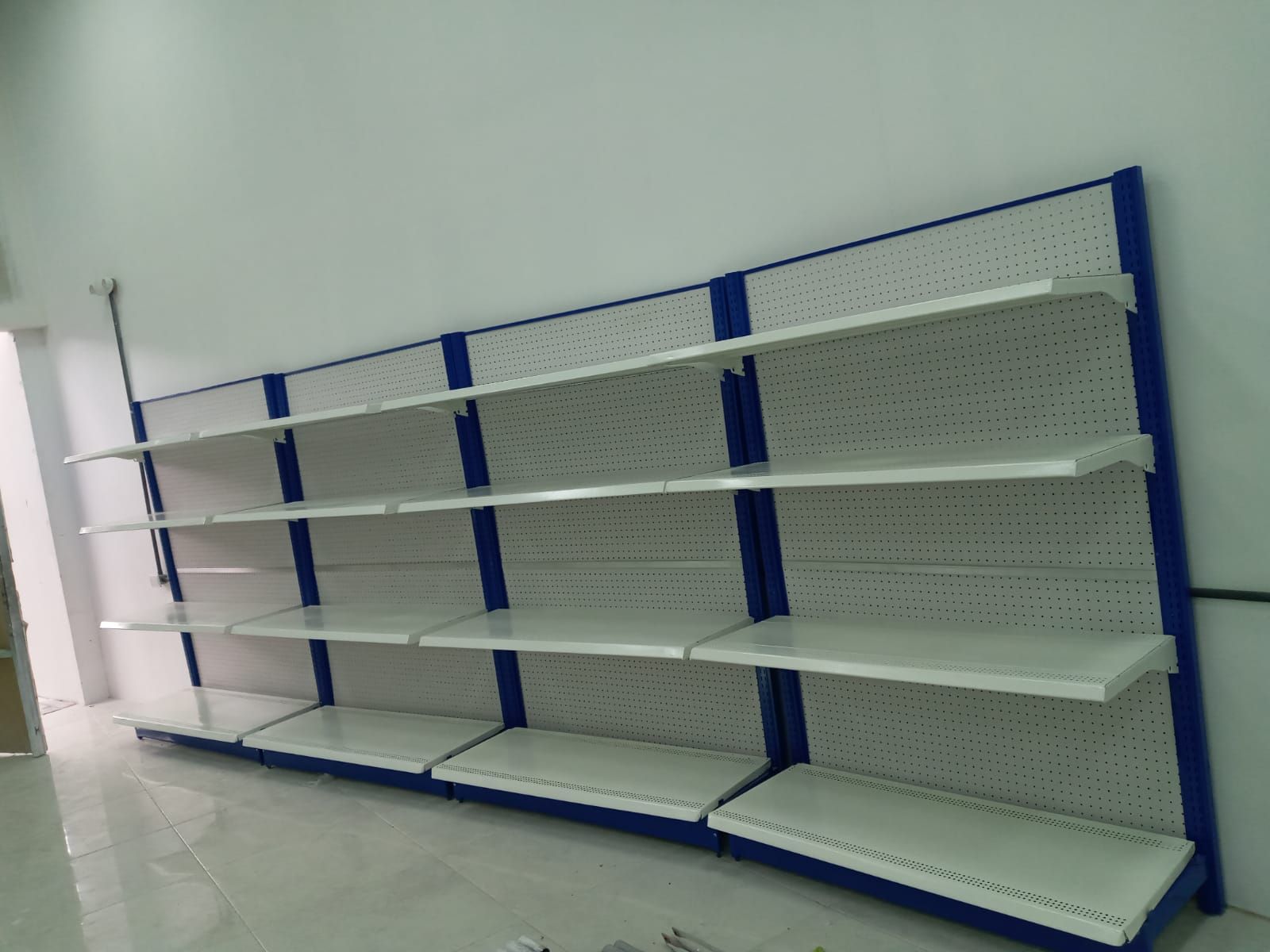 Una fila de estantes vacíos contra una pared blanca.