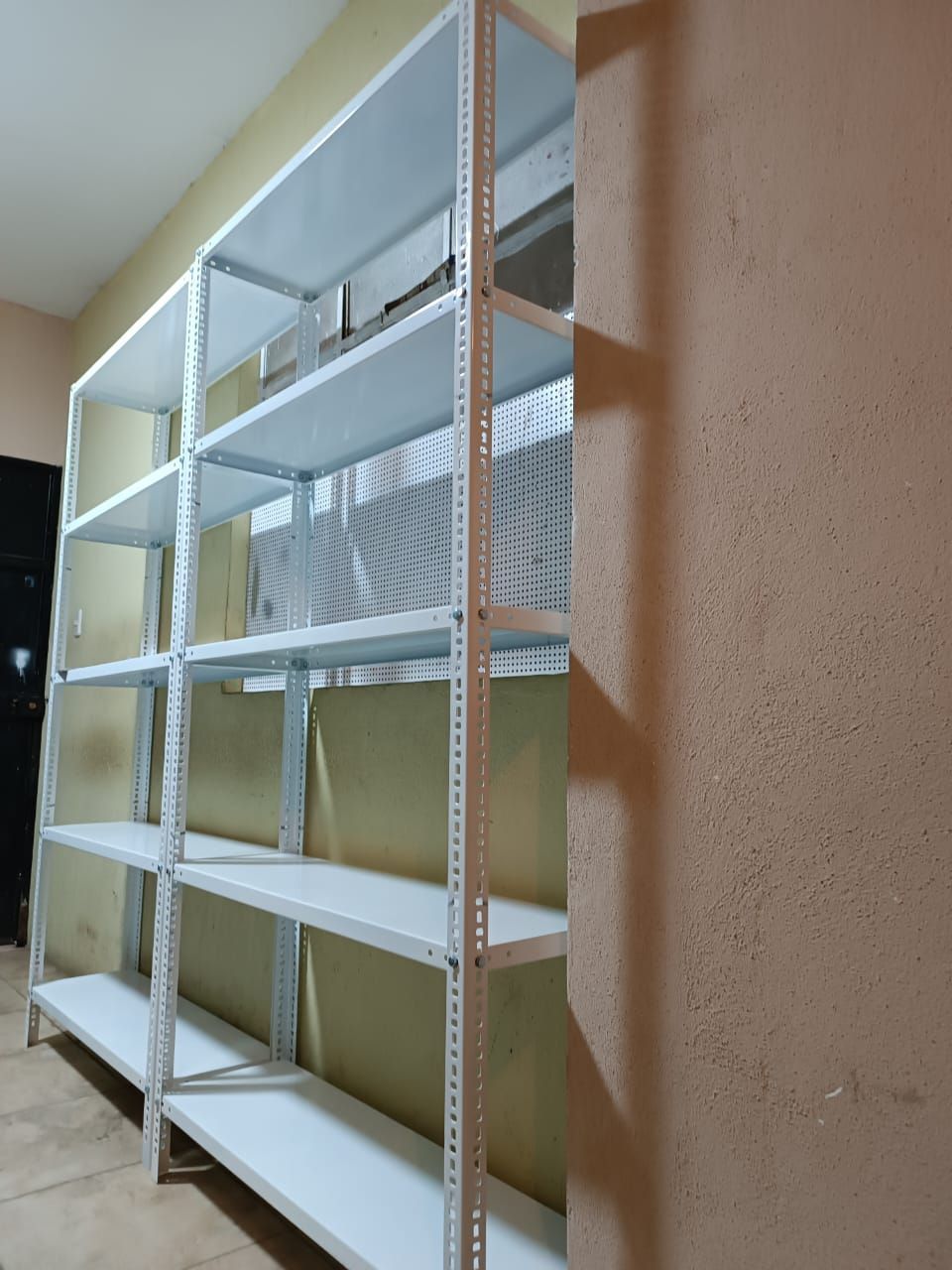 Una fila de estantes blancos contra una pared de una habitación.