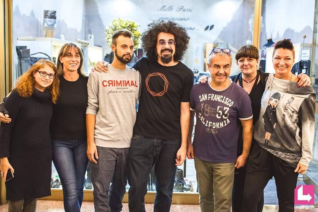 Un gruppo di persone che posano per una foto con un uomo che indossa una maglietta da criminale