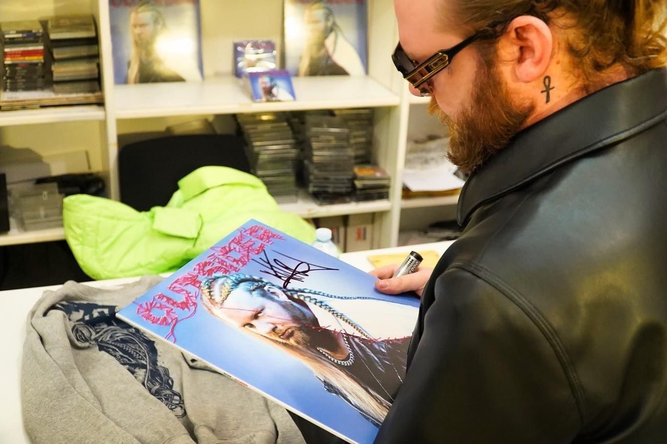 Un uomo con un tatuaggio sul collo sta firmando un disco