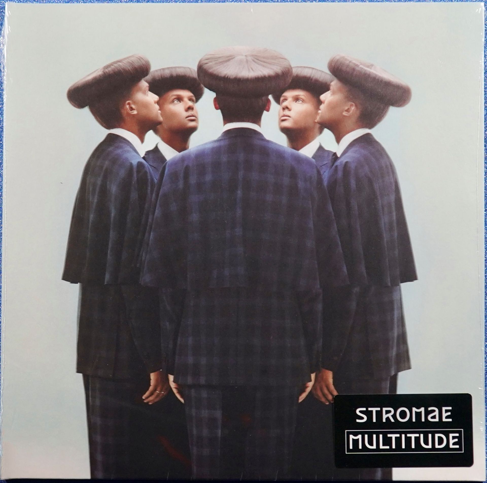 La copertina dell'album Stromae Multiplity presenta un gruppo di uomini in giacca e cravatta e cappelli