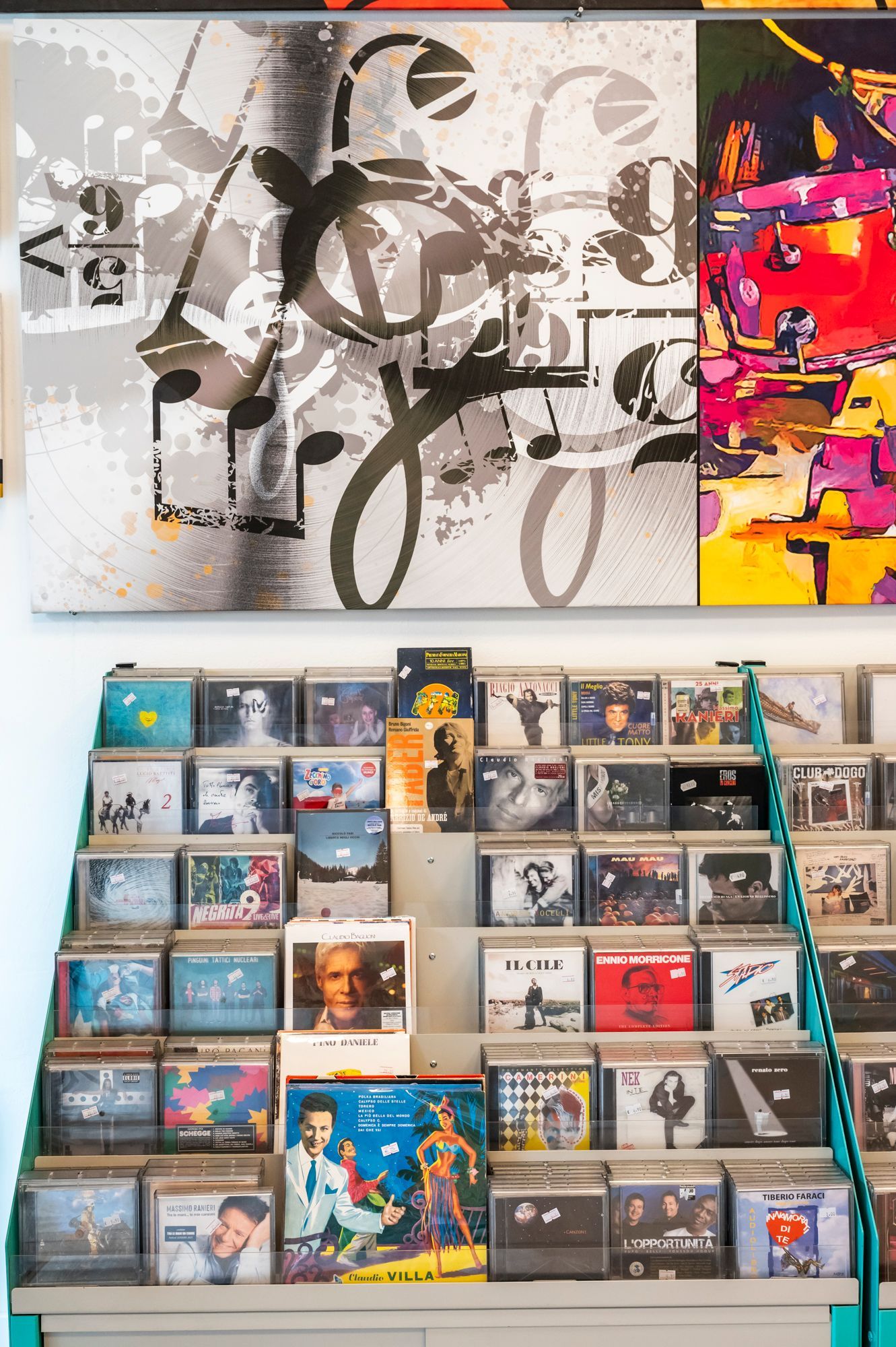 Uno scaffale pieno di cd e un dipinto sul muro.