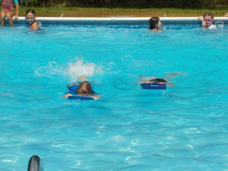 A group of children are swimming in a swimming pool.