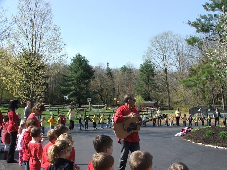 A little girl wearing a green shirt that says cool or rad is watering flowers