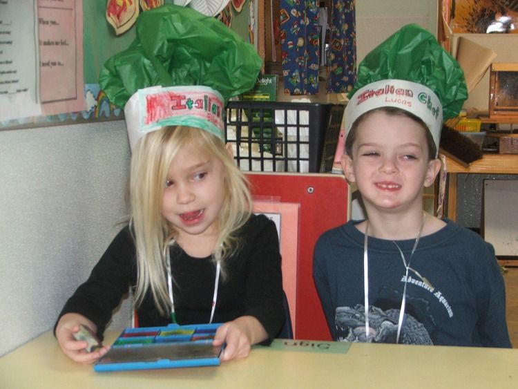 A boy and a girl wearing chef hats are sitting at a table