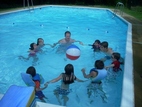 A group of children are playing with a beach ball in a swimming pool