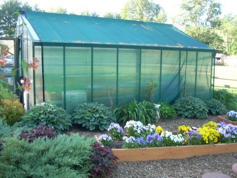 A greenhouse is surrounded by flowers in a garden