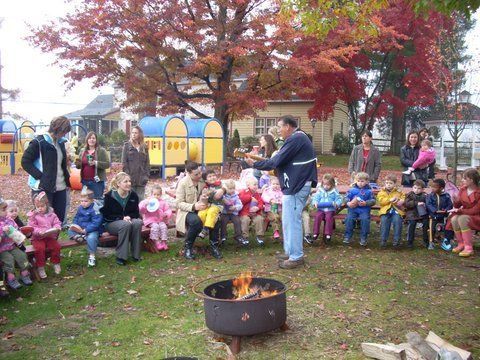 A group of children are sitting around a fire pit