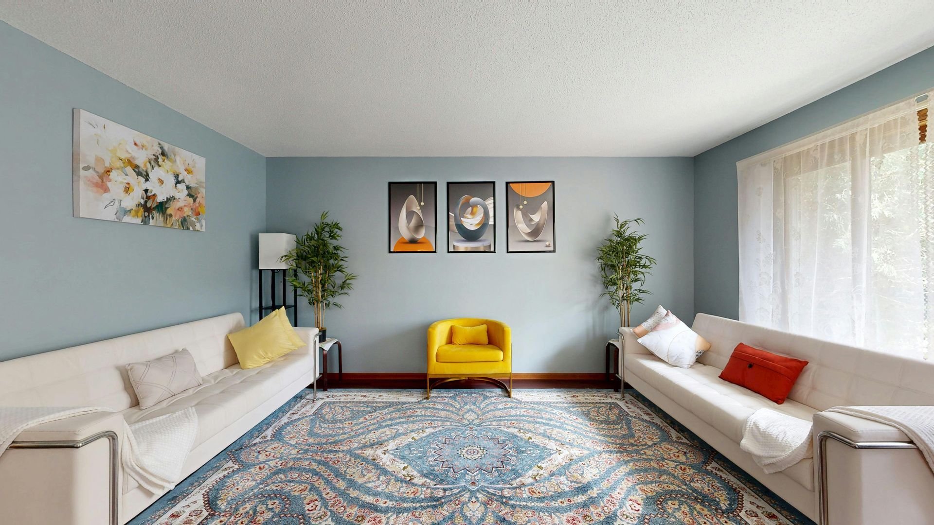 Living room with light blue walls, two cream-colored sofas, a bright yellow accent chair, and a patterned area rug.