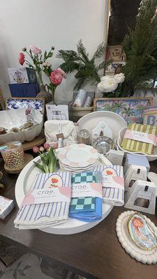 A display of kitchen linens, small plates, and decorative items arranged on a round white tray on a wooden table.